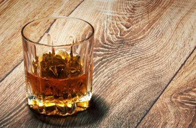 A glass of whiskey on a wooden surface