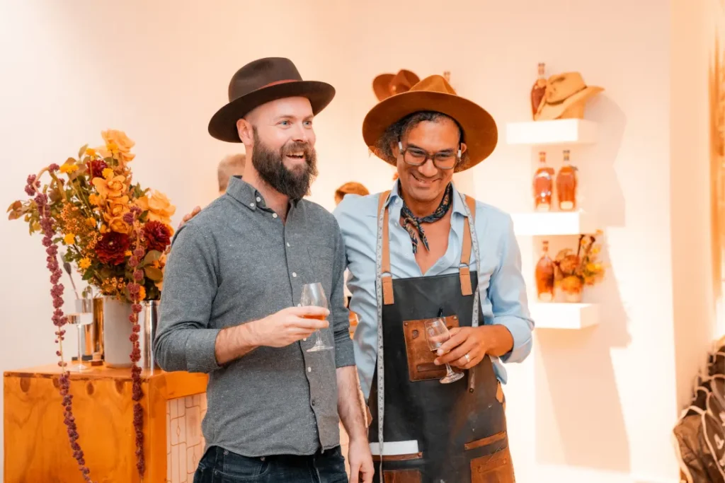 Two male figures in hats enjoying whiskey