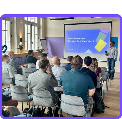 A small room with attendees looking at a speaker giving a presentation.